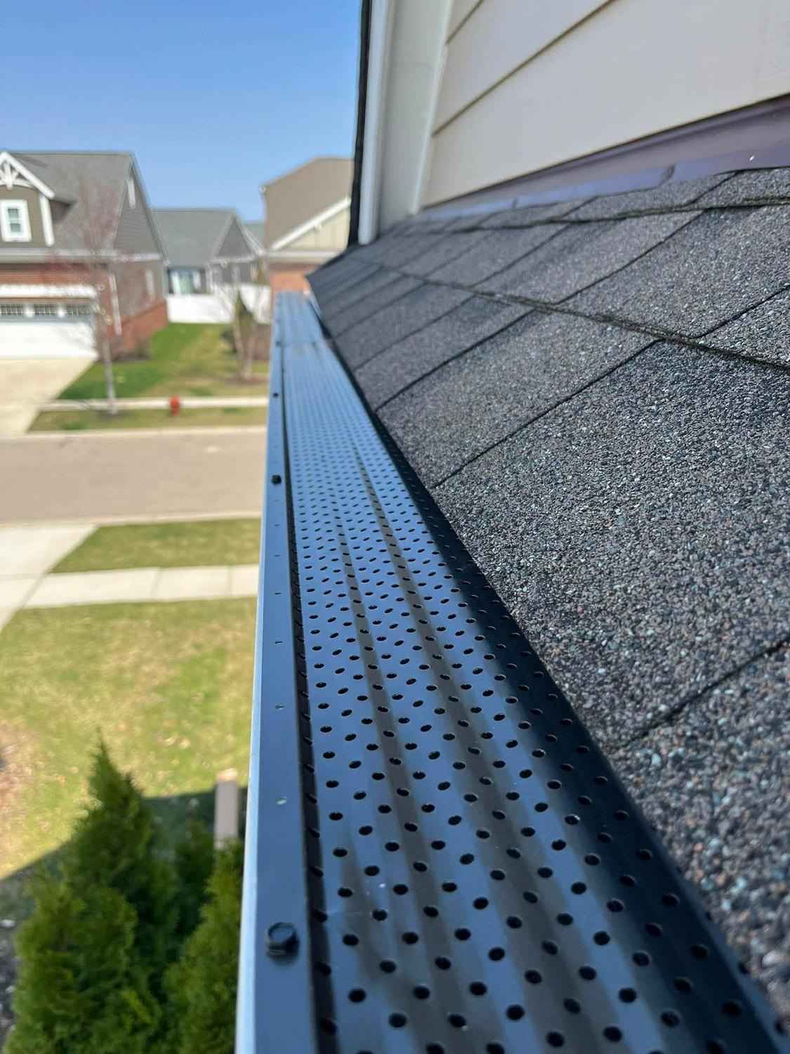 Black gutter guard covering a gutter on a suburban home
